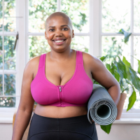 Pink compression bra on a model holding a yoga mat